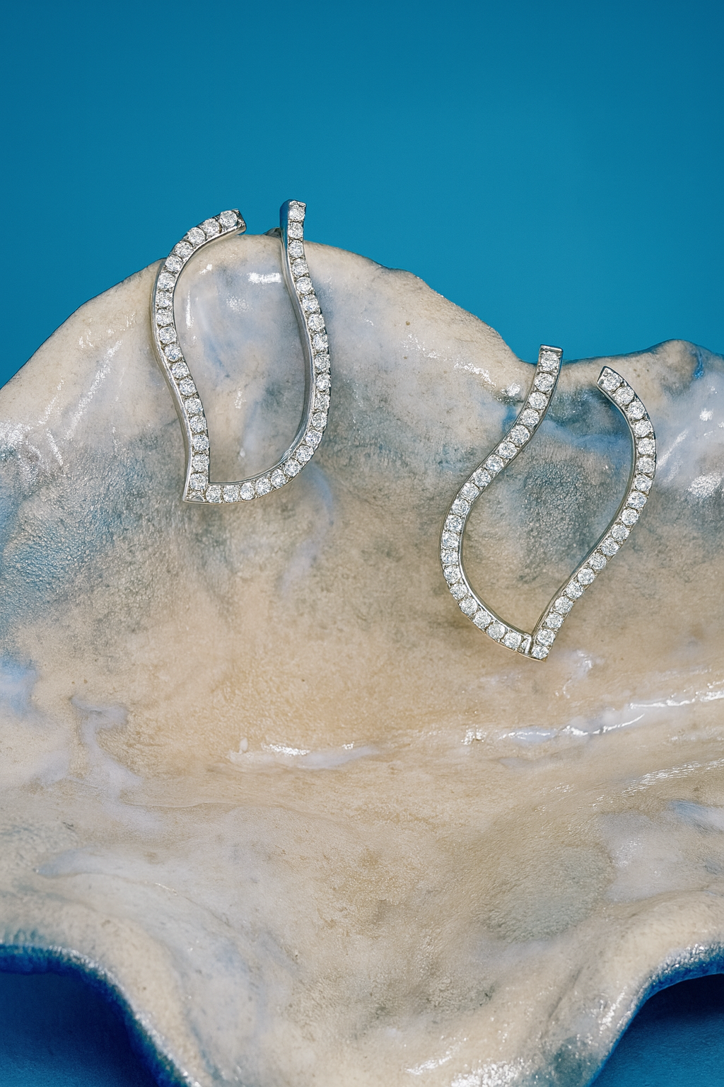 Création iconique DM Jeantet Joaillerie : boucles d’oreilles en or blanc 18 cts réinventant les créoles, serties de diamants 0,80 ct en pavage micro-griffe – un mouvement qui évoque les vagues.